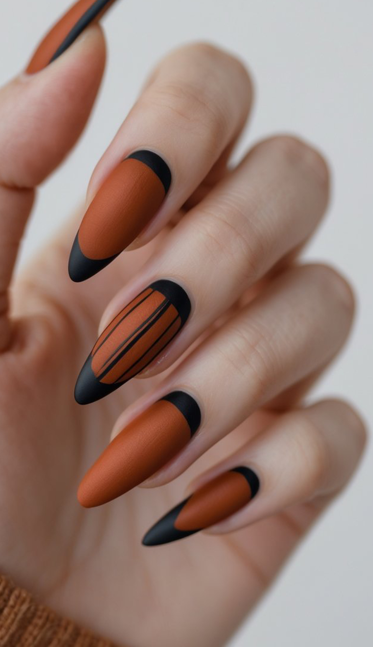 Dramatic black tips, graphic stripes, and a burnt orange base pop on these long almond nails. If you want little edge in your autumn mani, go for this design!