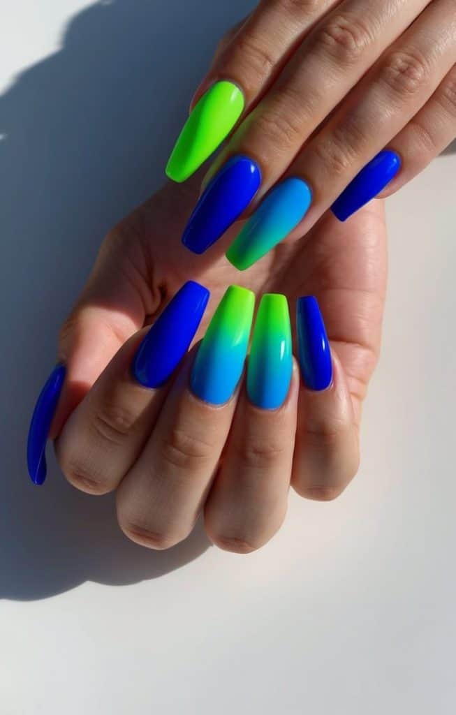 Electric blue and neon green gradient ombre nails on a sleek, modern surface, catching the light