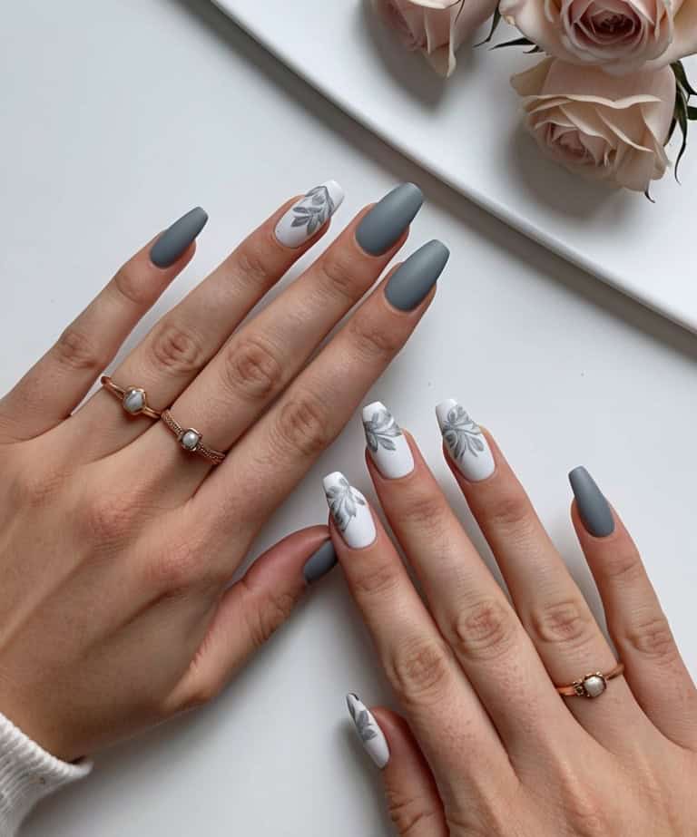 Blooms and leaves decorate white accent nails in a matte gray manicure