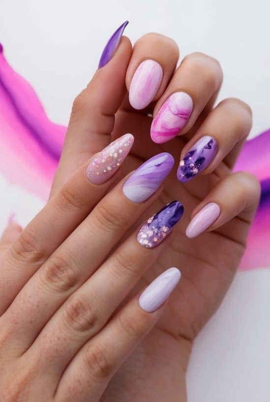 Soft pink and purple nails with marbled swirls and glitter accents