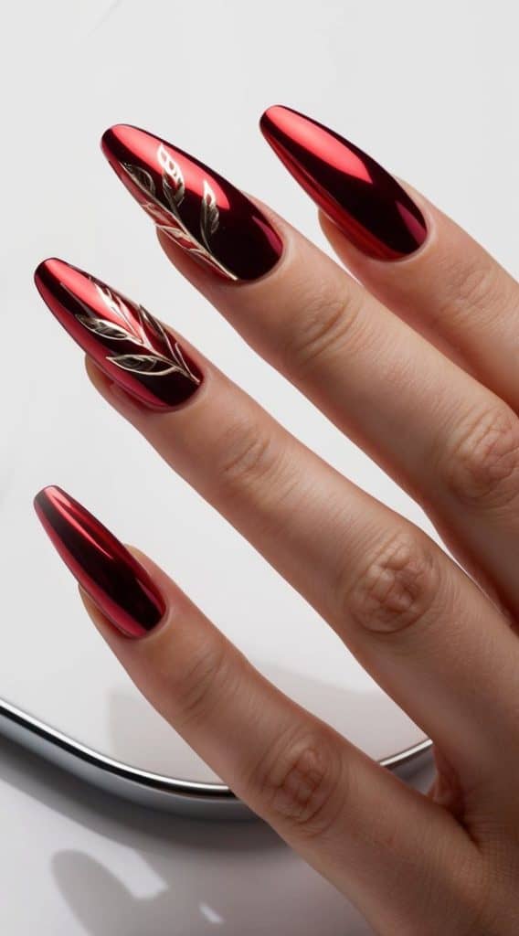 A gold leaf design on scarlet red chrome nails