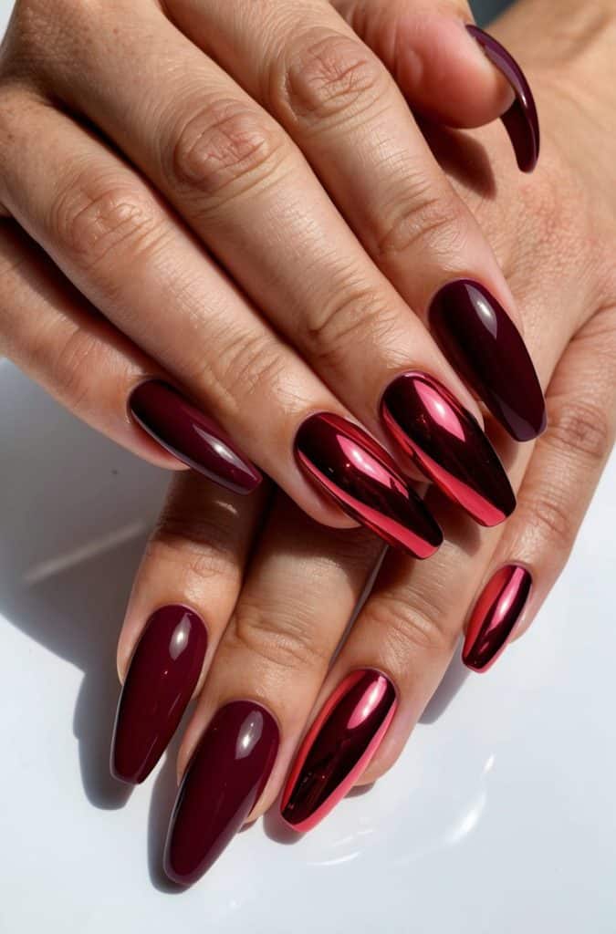 A hand with glossy maroon and red chrome nails, reflecting light