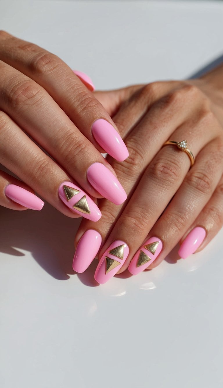 Bubblegum pink nails with gold triangle designs on a clean, white background