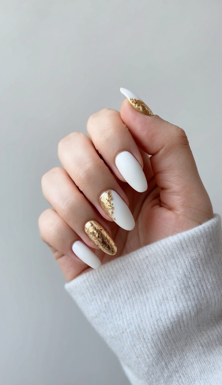 Modern matte white nails with gold foil accents for a sleek and elegant manicure look.