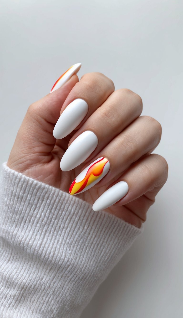 Almond-shaped matte white nails with one featuring bold flame-like red, orange, and yellow swirl art.
