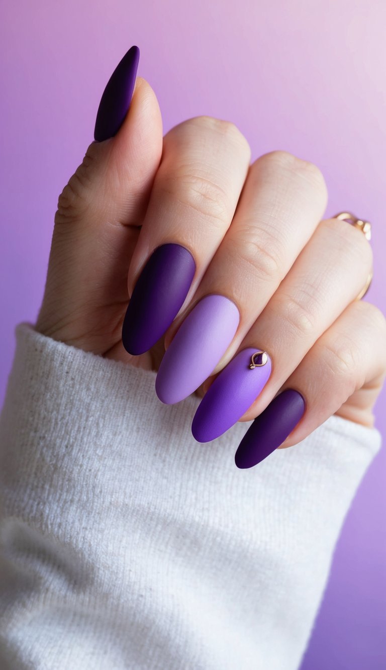 Almond-shaped nails in matte purple hues with a subtle gold gem accent, blending soft lilac and bold violet tones.