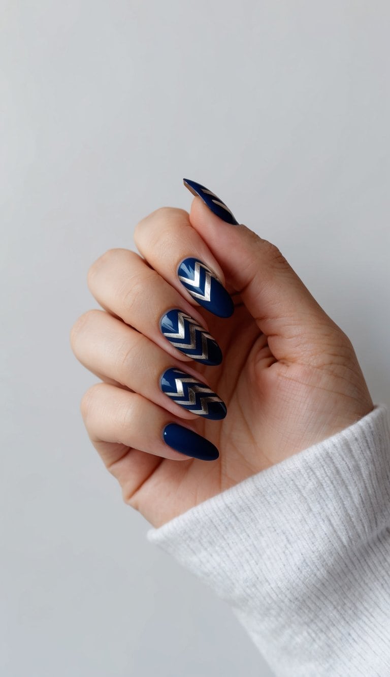 A close-up view of navy blue nail art with metallic chevron patterns on a clean, minimalist background