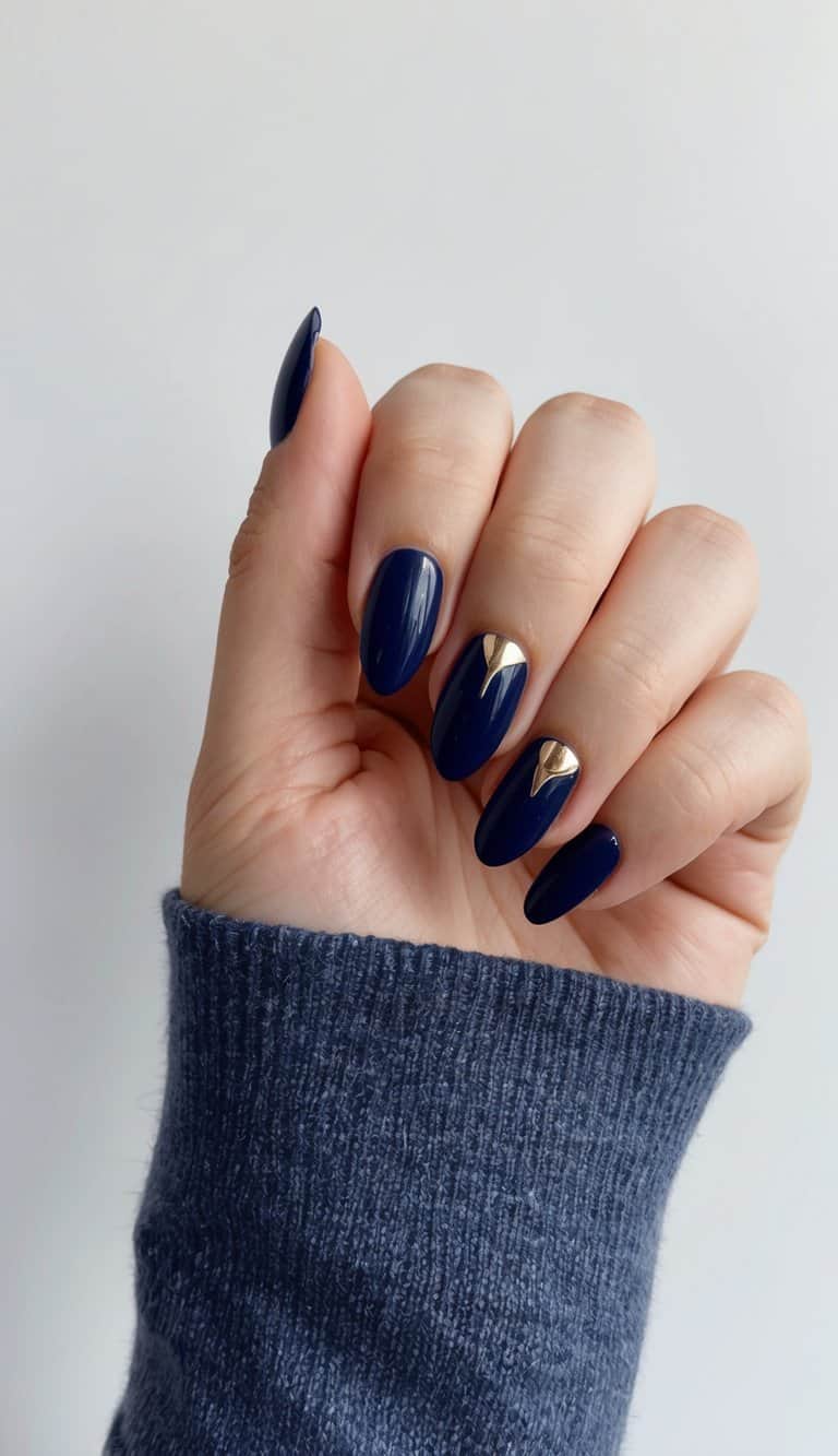 A close-up of navy blue nails with metallic accents, against a negative space background