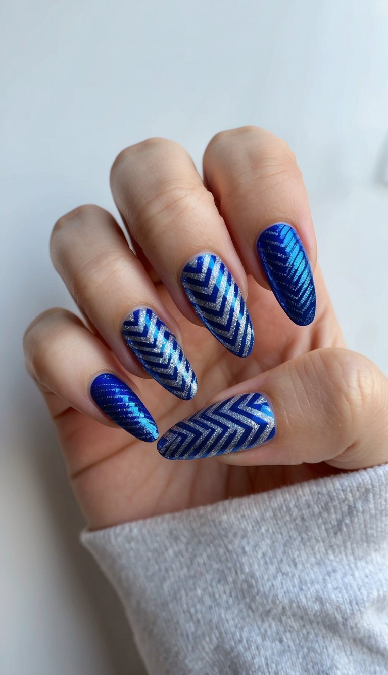 Metallic blue and silver nails with bold chevron designs across each nail, offering a striking and modern nail art style.