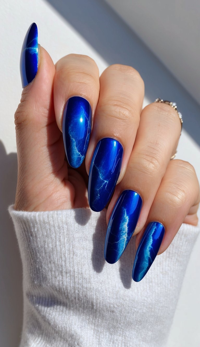 A close-up of blue chrome nails with a marble effect, reflecting light and color