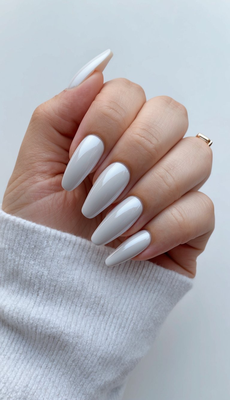 A hand holding a white chrome French tip nail with elegant and sleek design