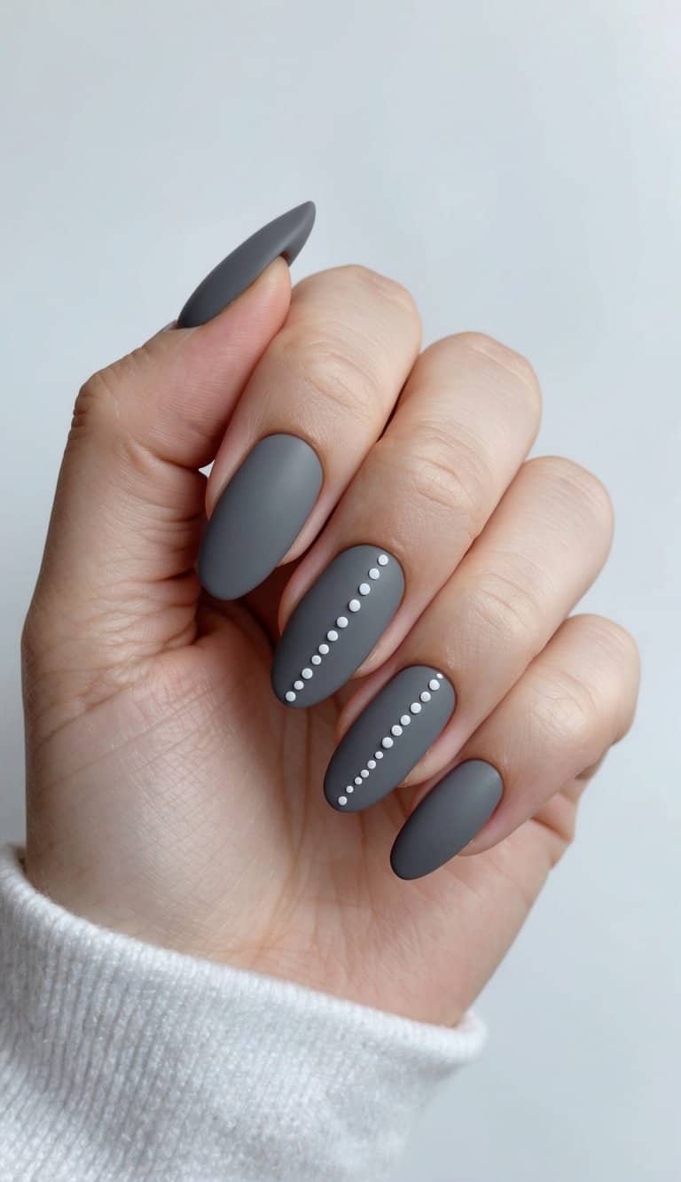 A close-up of matte gray nails with minimalist dot designs