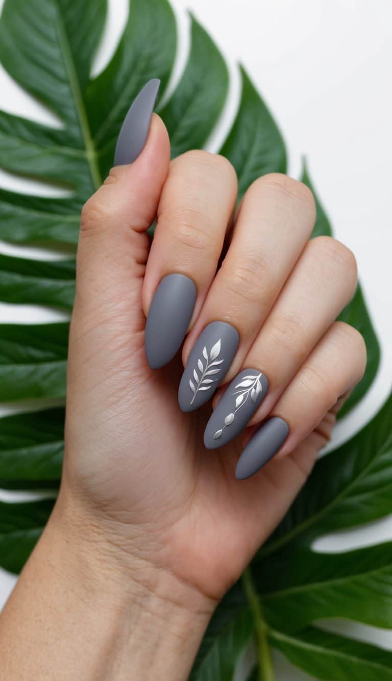 A close-up of matte gray nail art designs on leafy green background