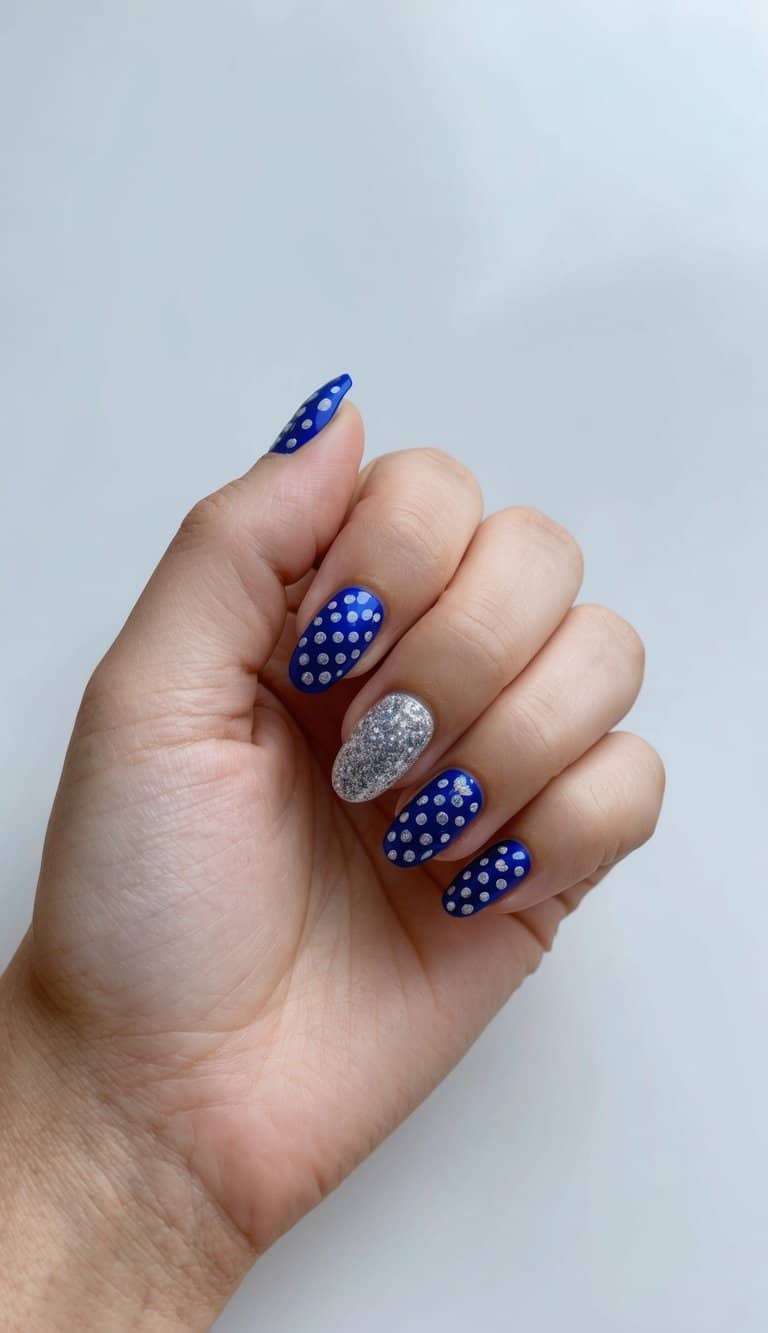 A royal blue and silver polka dot nail art design on a clean, manicured surface