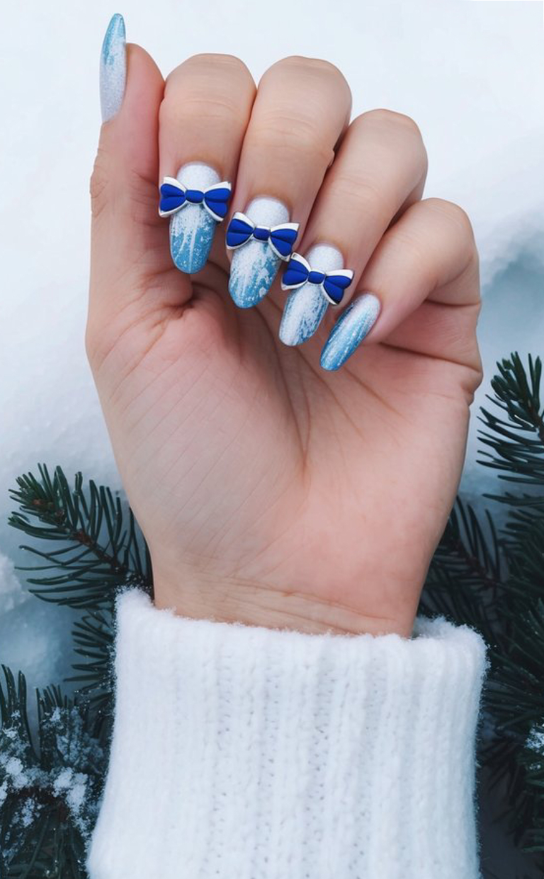 Nails with snowy blue tips, icy ombré, and adorable blue 3D bows, looking magical and chic