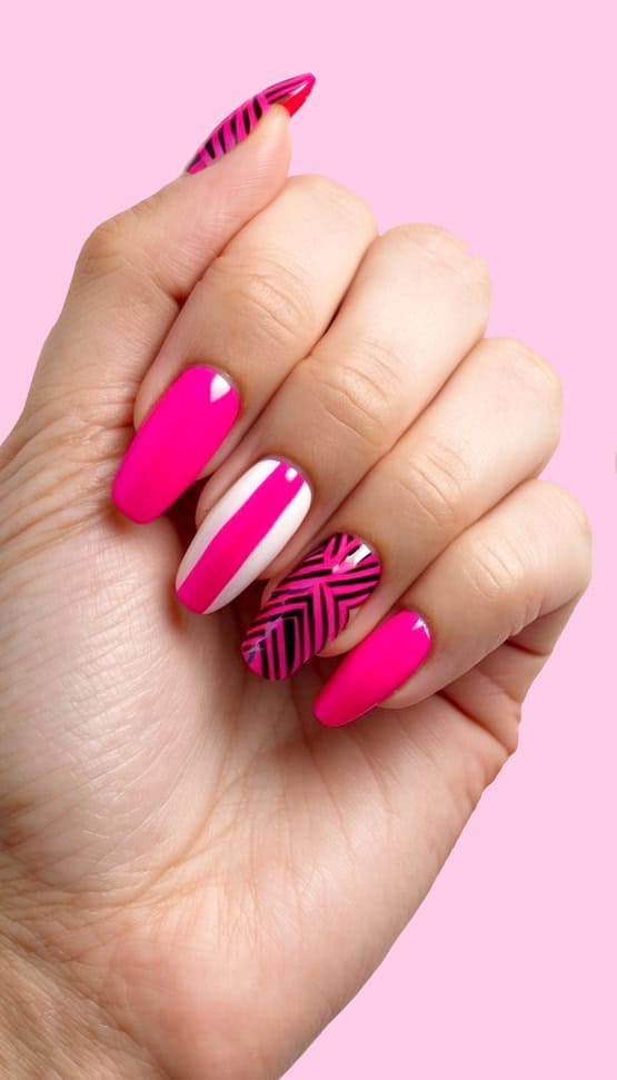 This bold nail design pairs glossy hot pink with a sleek white accent and striking black geometric patterns