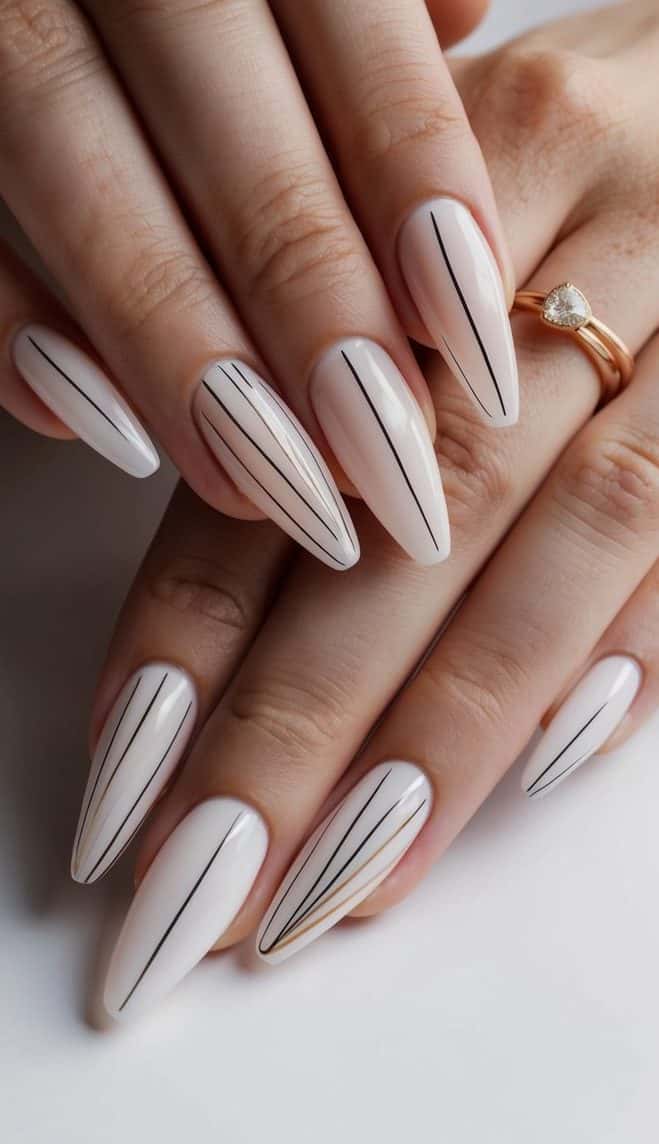 Thin black and gold lines elegantly cascade down a crisp white base in this nail design