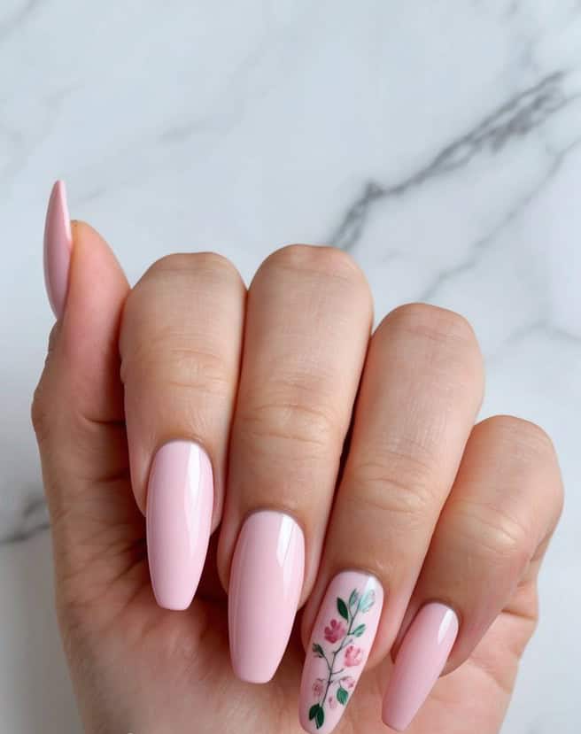 Soft pink nails arranged on a white marble background with delicate floral accents and a cupid's arrow motif