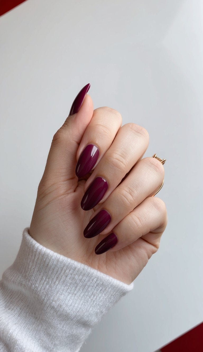 A hand with burgundy French tips against a glossy red background