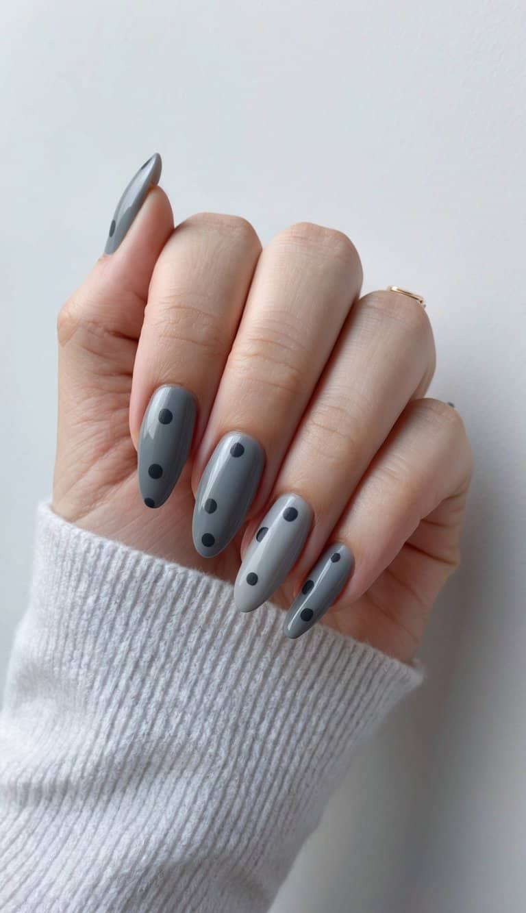 A close-up of elegant gray nails with retro charcoal polka dot designs, against a matte finish backdrop
