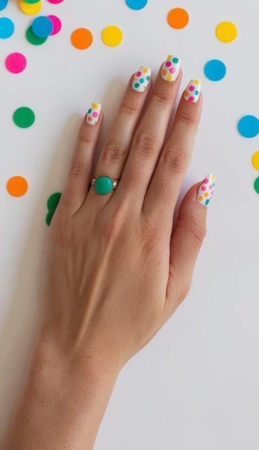 A table scattered with colorful polka dot nail art designs and party decorations