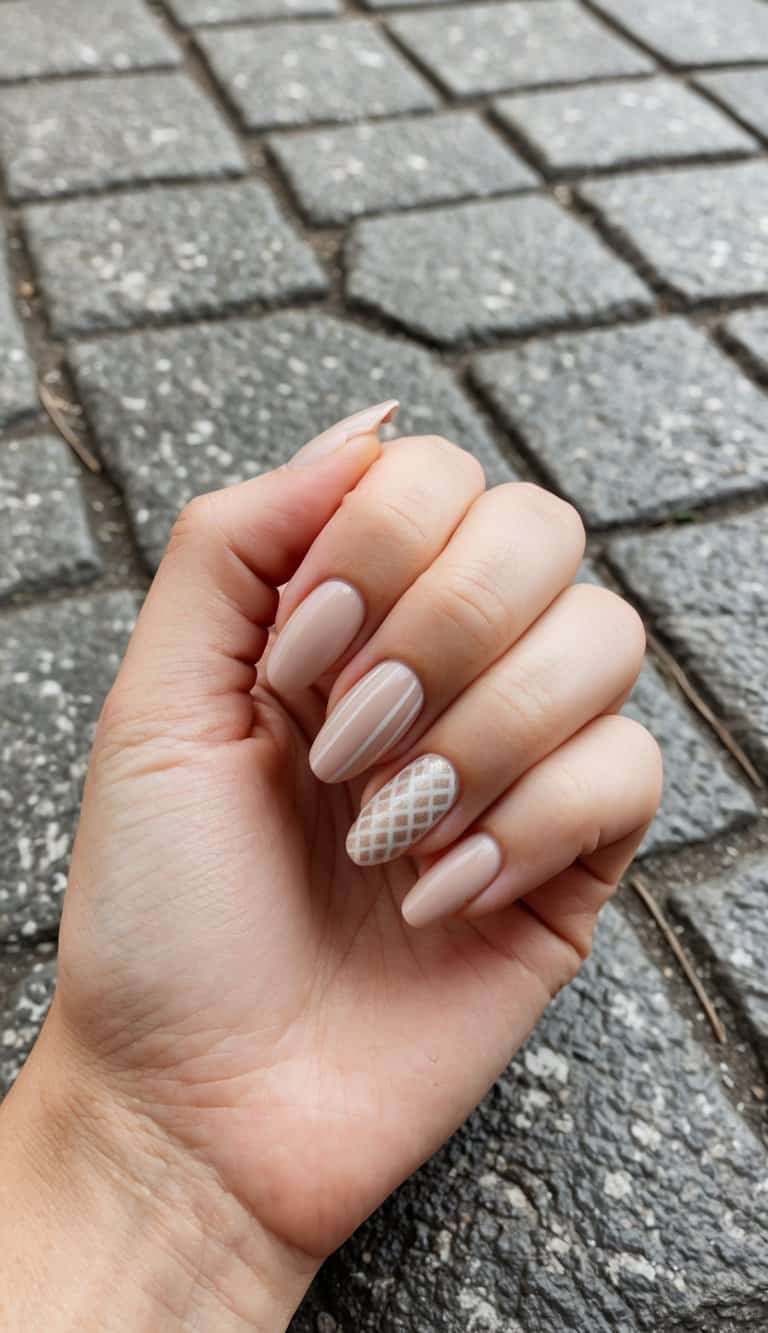 A close-up of neutral tone nail art on a textured cobblestone surface