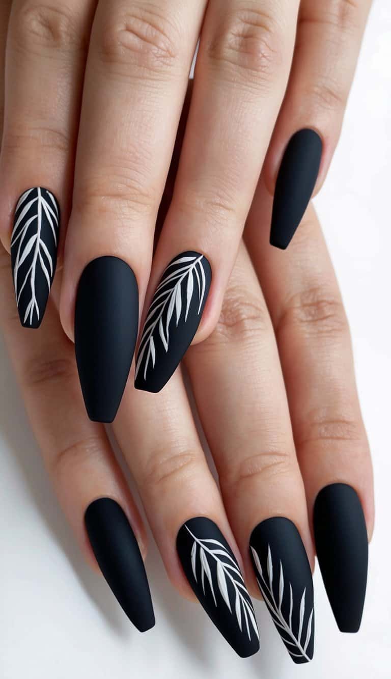A close-up of matte black nails with a leaf pattern design