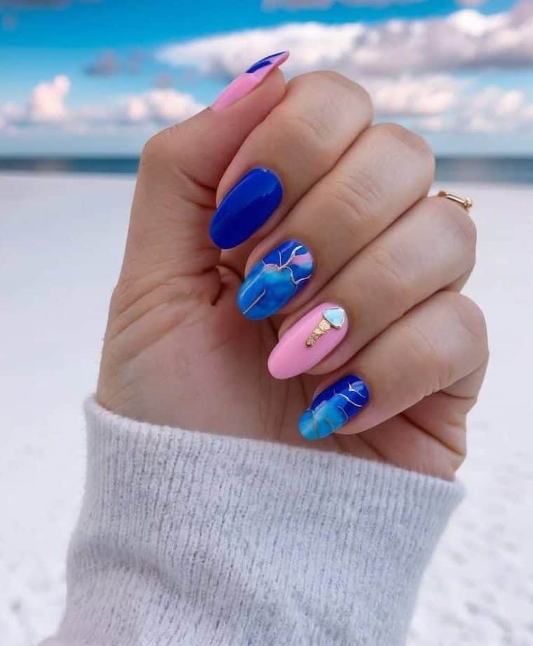 A luxurious blue marble design featuring delicate gold veining, paired with a soft pink accent nail adorned with sky-blue and gold rhinestones.
