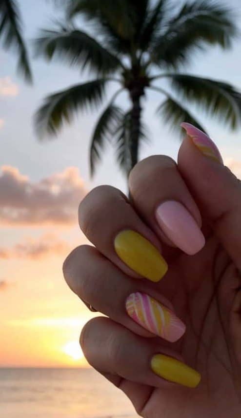 A serene sunset over a tropical beach, with palm trees silhouetted against the colorful sky, casting a warm glow over the pink and yellow nail art designs