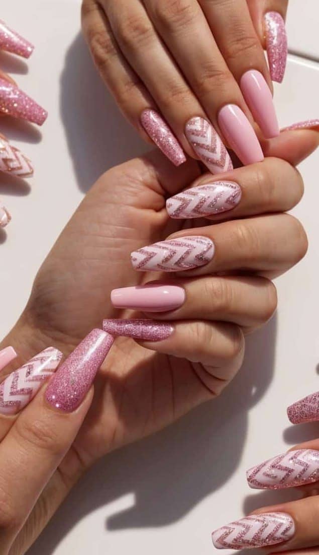 Pink glitter nail art designs displayed on a sleek white backdrop, featuring various chevron patterns