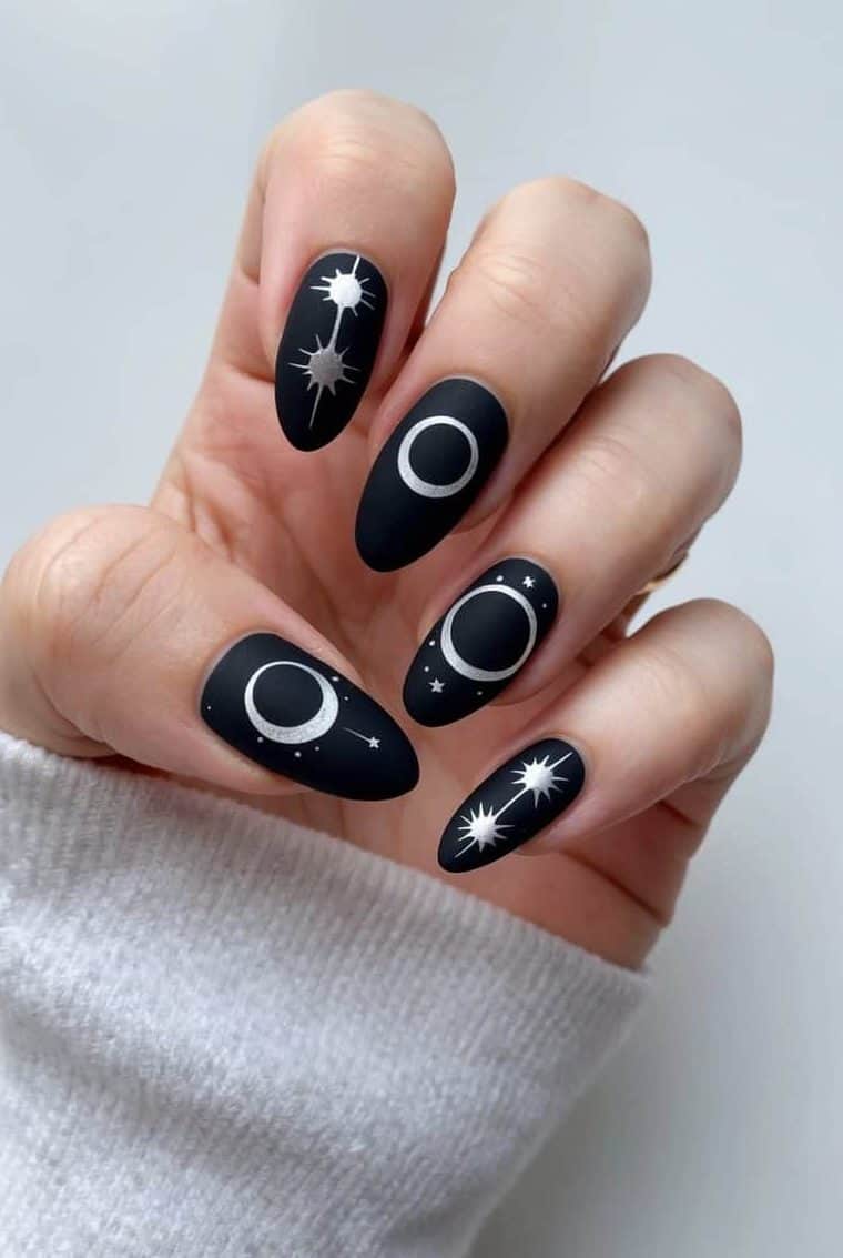 A lunar eclipse themed nail art design with bold and edgy matte black patterns, featuring celestial elements and geometric shapes
