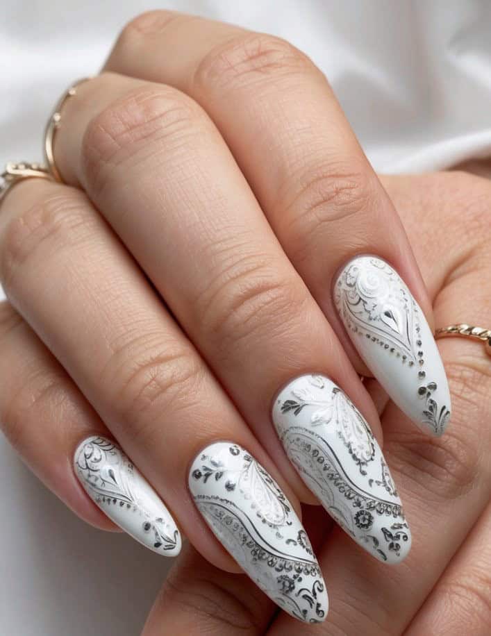 A close-up of intricately designed paisley nail art on a bridal theme, with delicate and elegant patterns in white and silver tones