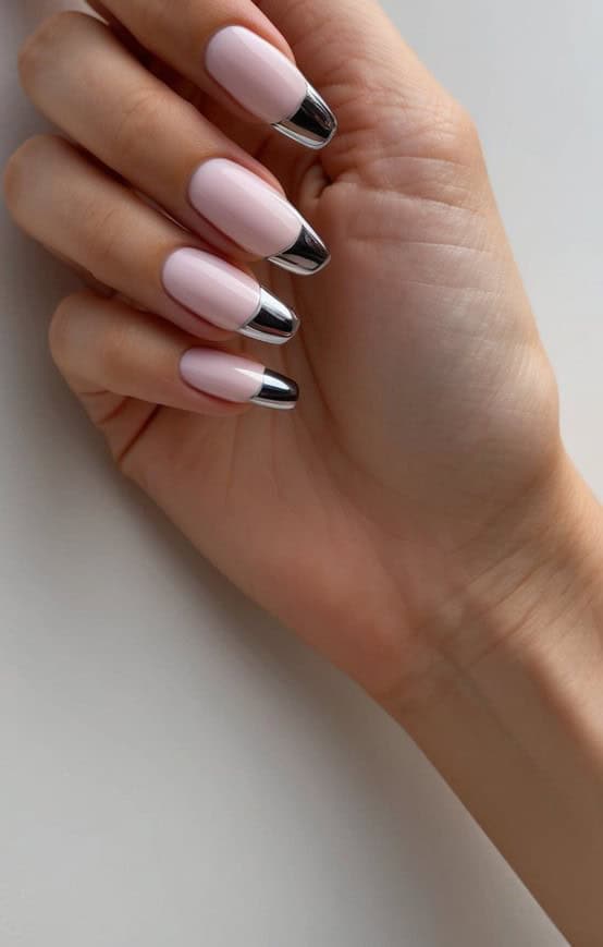 Soft pink nails with silver chrome tips displayed on a clean, neutral surface