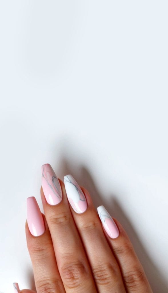 Soft pink nails with marbled designs on a clean, white background