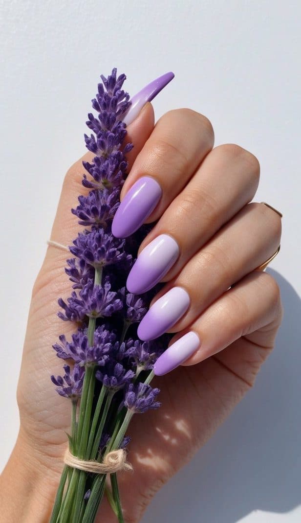 A delicate hand with lavender gradient nails holding a bouquet of lavender flowers