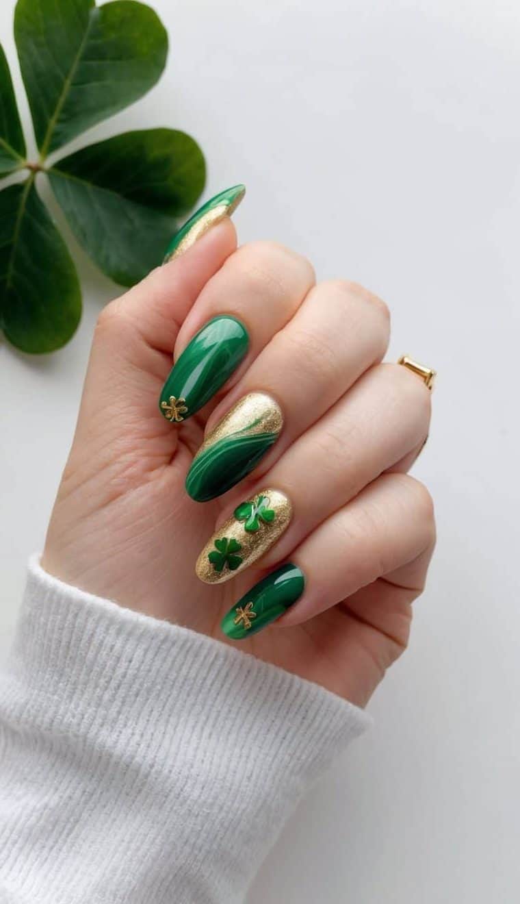 A green and gold marble nail art design with shamrock accents