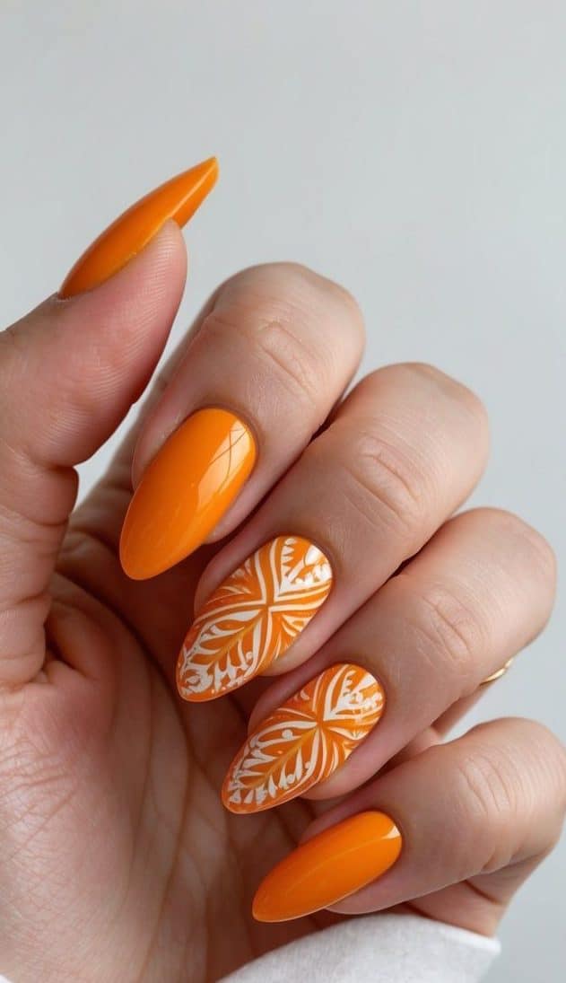 A vibrant orange almond nail art design featuring intricate patterns and details