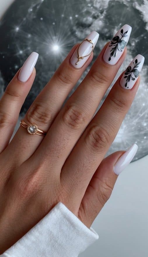 Elegant white nails with intricate black floral patterns, soft blue details, and a gold embellishment, adding a chic and refined look to this formal nail art design.