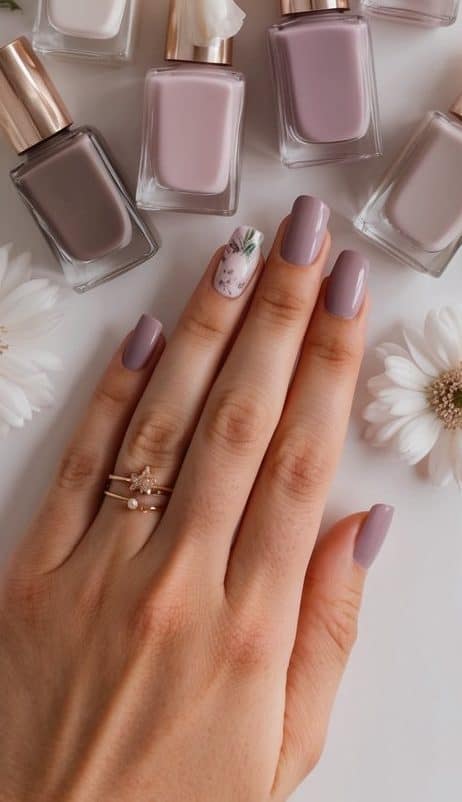 Soft mauve nail polish bottles arranged in a gradient from dark to light, surrounded by delicate floral accents