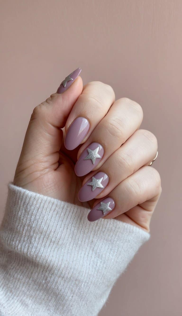 A close-up of mauve and silver star nail art on a soft dusty pink background
