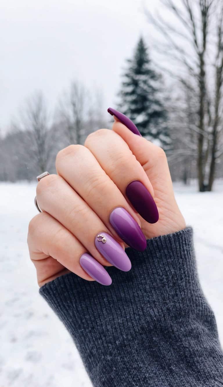 A close-up of maroon and purple ombre nails against a winter-themed background