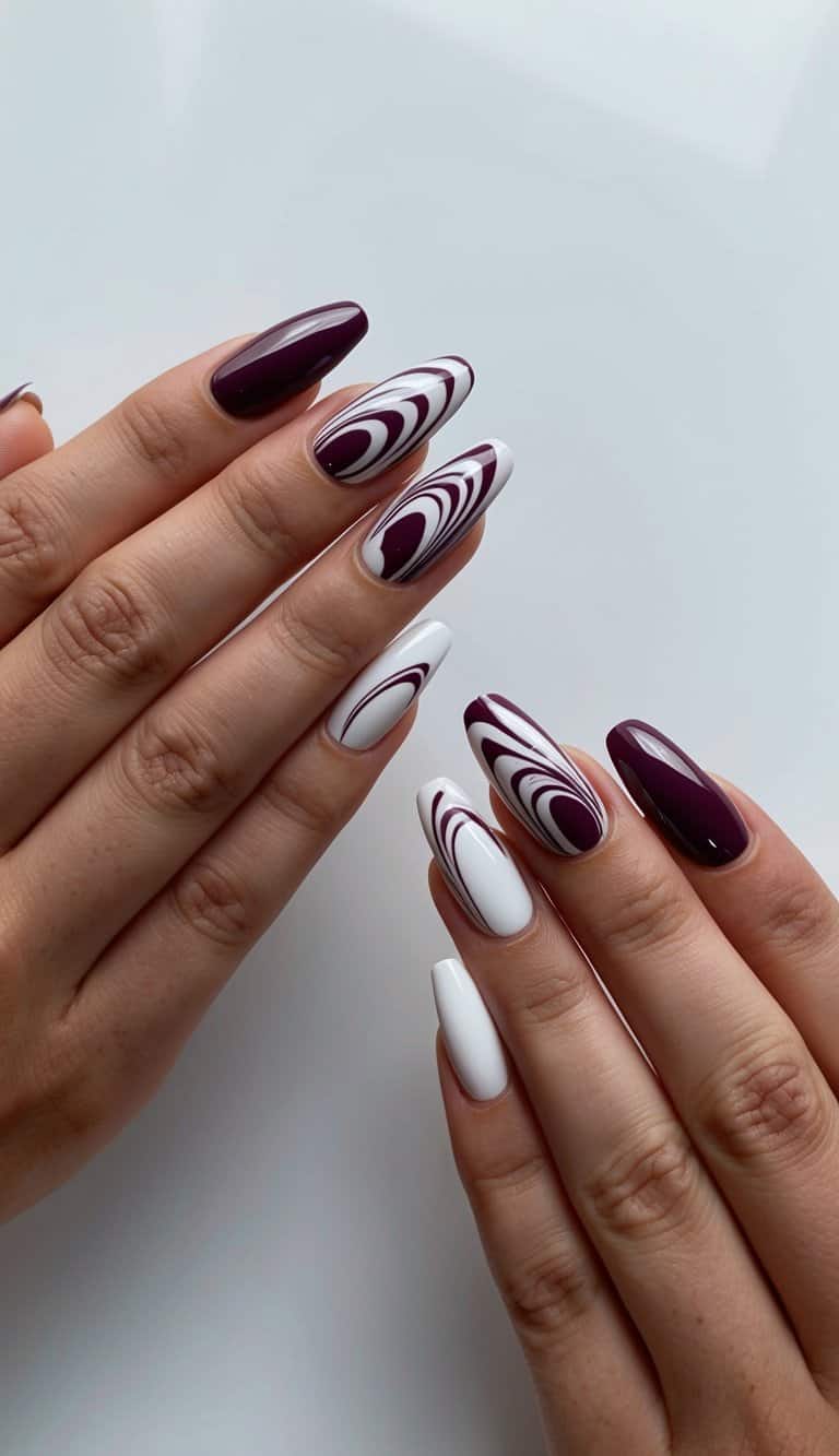 A close-up of maroon and white swirl nails on a sleek, modern background