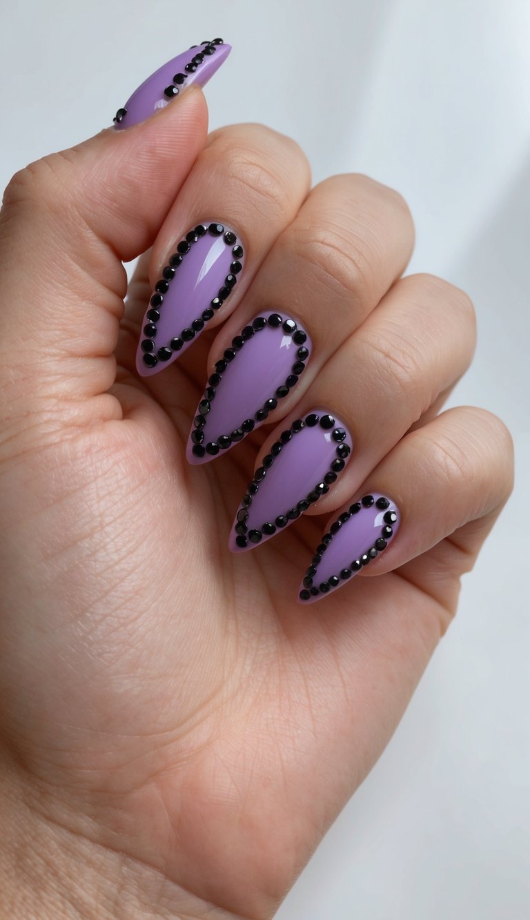 A close-up of purple and black rhinestone crescent tips on nails