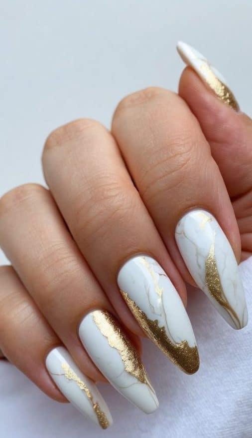 A close-up of elegant marbled white and gold nail art