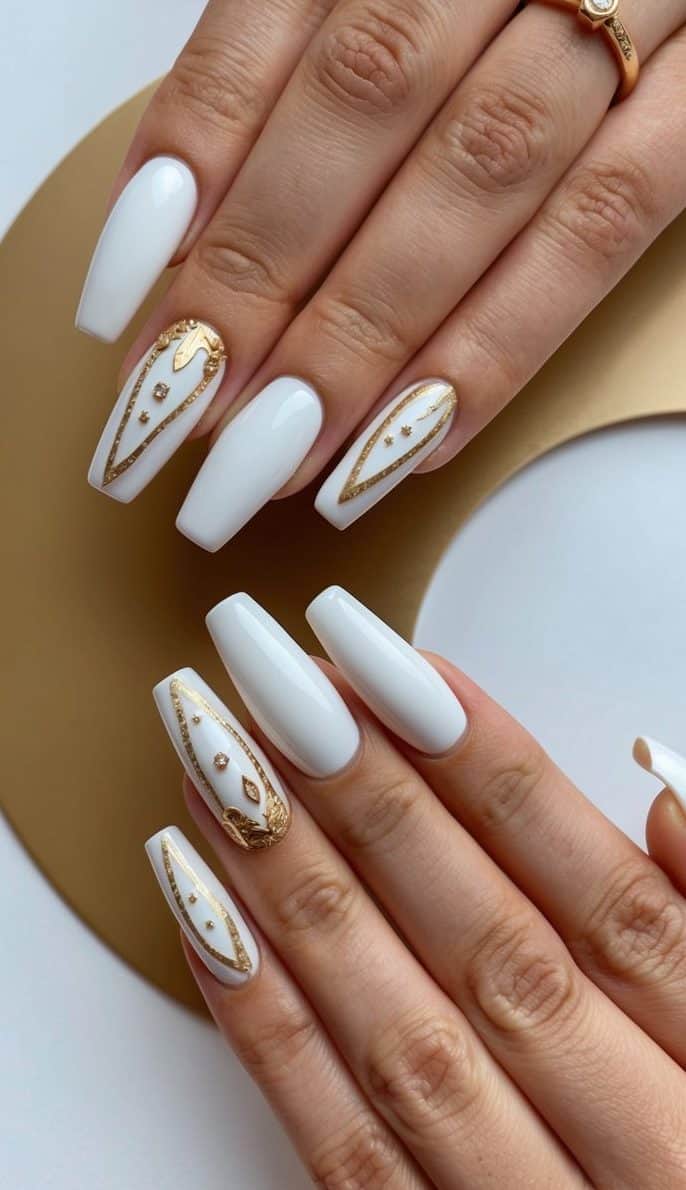 A close-up of white and gold nail art design on a half-moon background