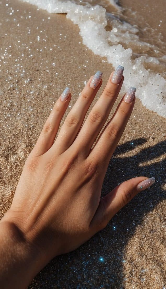 A sandy beach with sparkling flakes of glitter scattered across the shore, with waves gently lapping at the edge