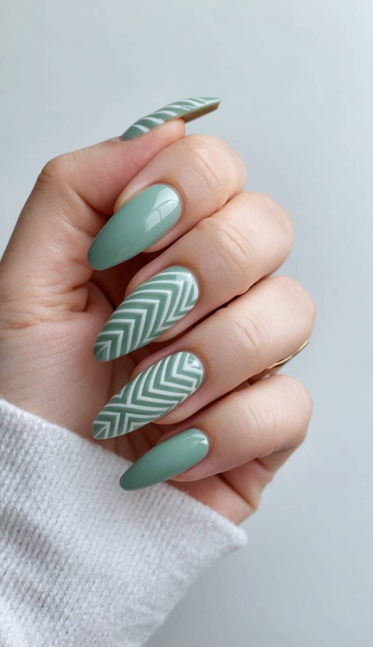 A close-up of sage green nails with intricate geometrical patterns