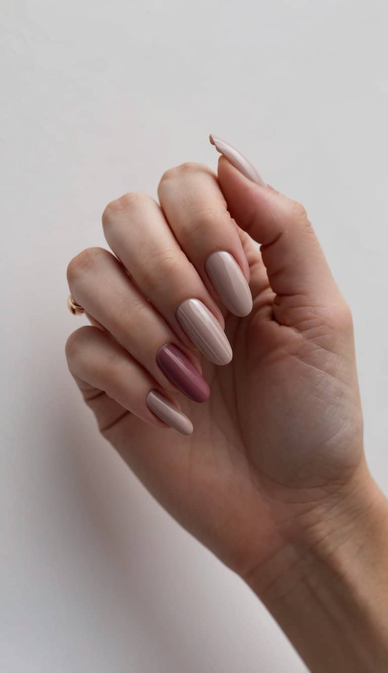 A sleek, minimalist nail art design with neutral tones and a pop of cranberry color