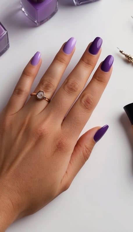 A table with various shades of purple nail polish bottles, alongside small nail art tools and accessories