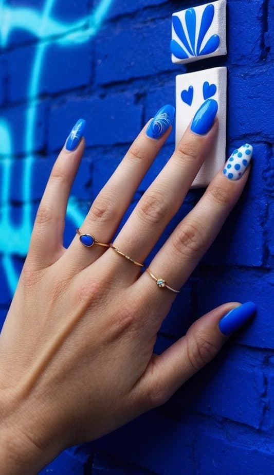 A creative blue nail art design with swirls, polka dots, and solid finishes, featuring an electric blue shade for a playful yet chic manicure.